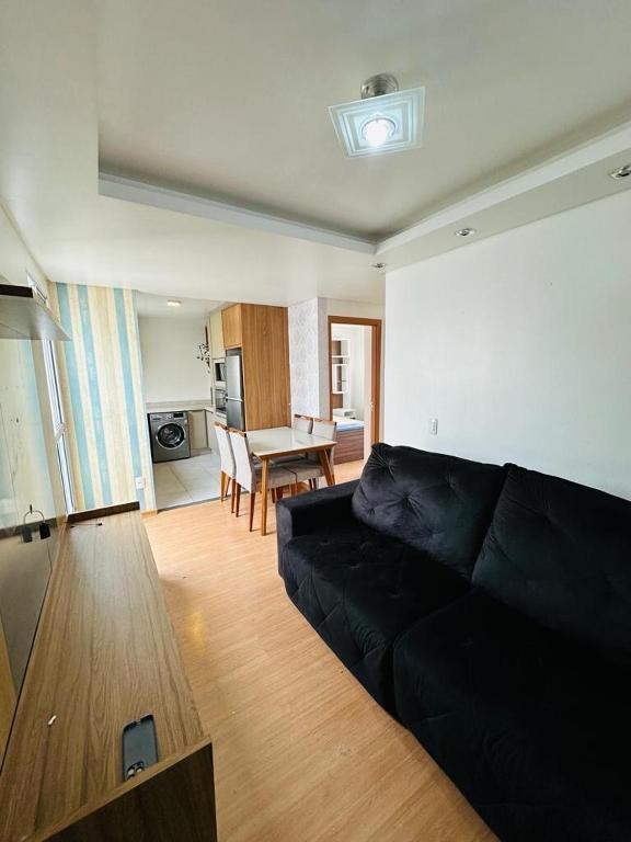 a living room with a black couch and a table at Ap 2 Quartos 5km da BR, Palhoça in Palhoça
