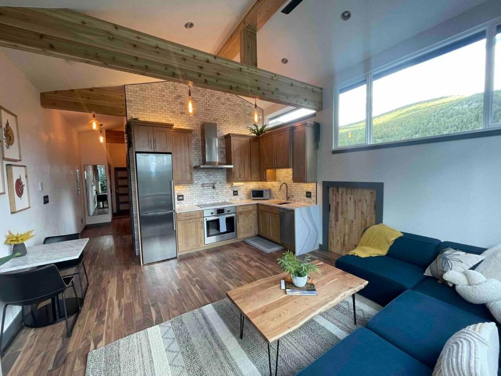 a living room with a blue couch and a kitchen at Blue Owl - Tree House Views! Couples Getaway! in Idaho Springs