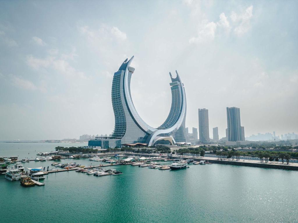 un groupe de bâtiments avec des bateaux dans un plan d'eau dans l'établissement Raffles Doha, à Doha