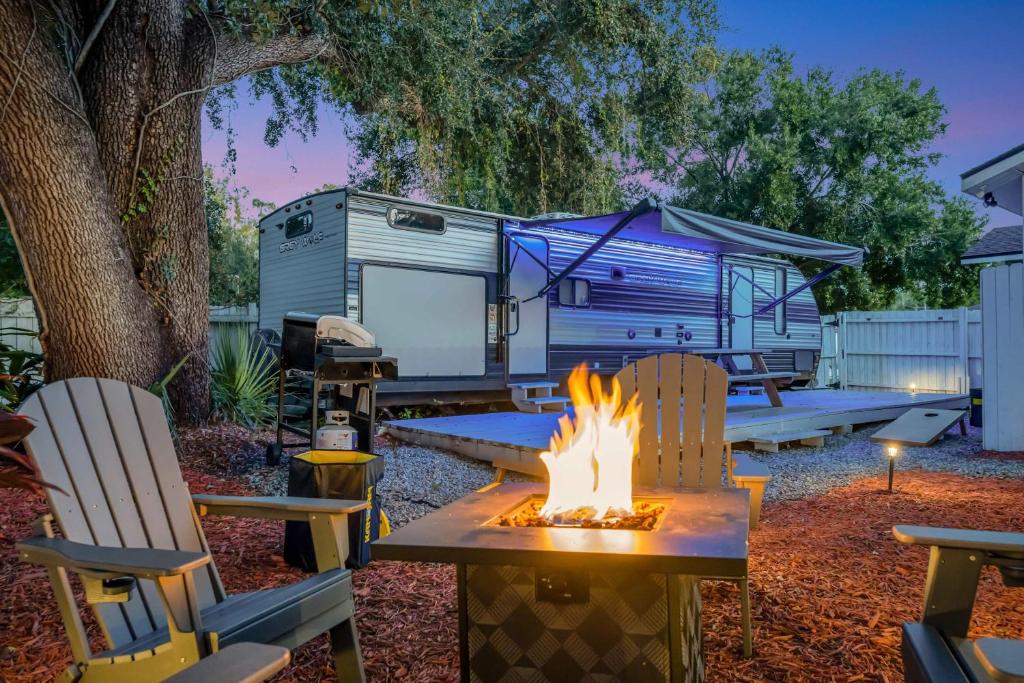 a campsite with a campfire and a trailer at The Backyard Glampground - Camper Fire Pit & Games in Tampa
