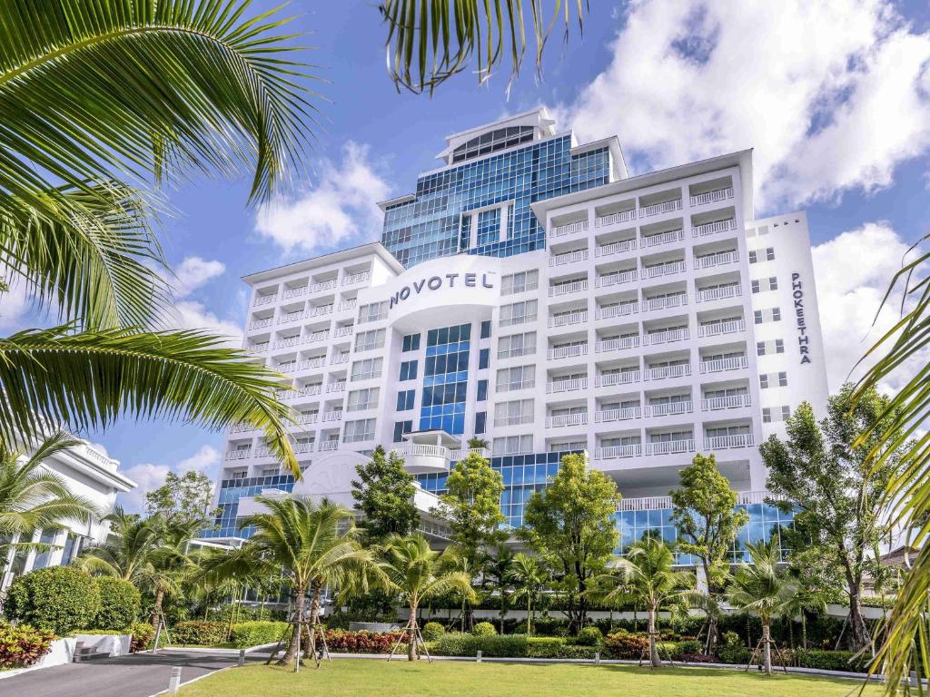 an office building with palm trees in front of it at Novotel Phuket City Phokeethra in Phuket Town