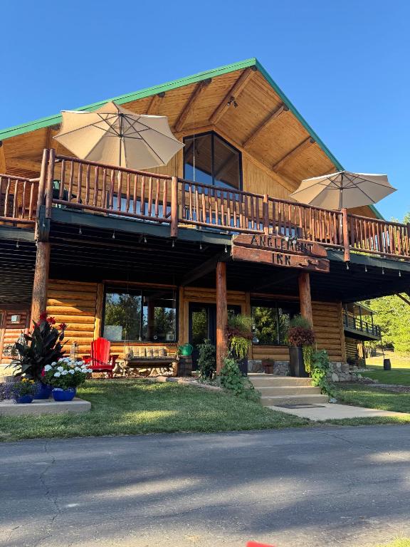 a large wooden house with a balcony with umbrellas at Anglemont Inn in Anglemont