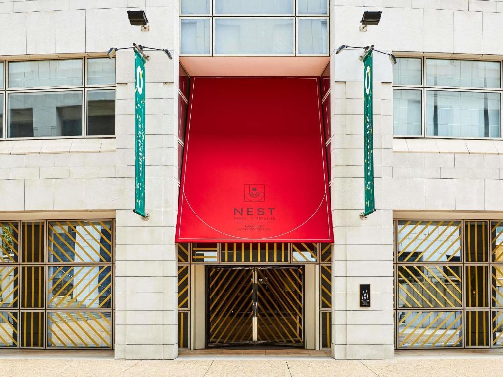 a facade of a building with a red next sign at Nest Hotel Paris la Défense - MGallery Collection in Puteaux