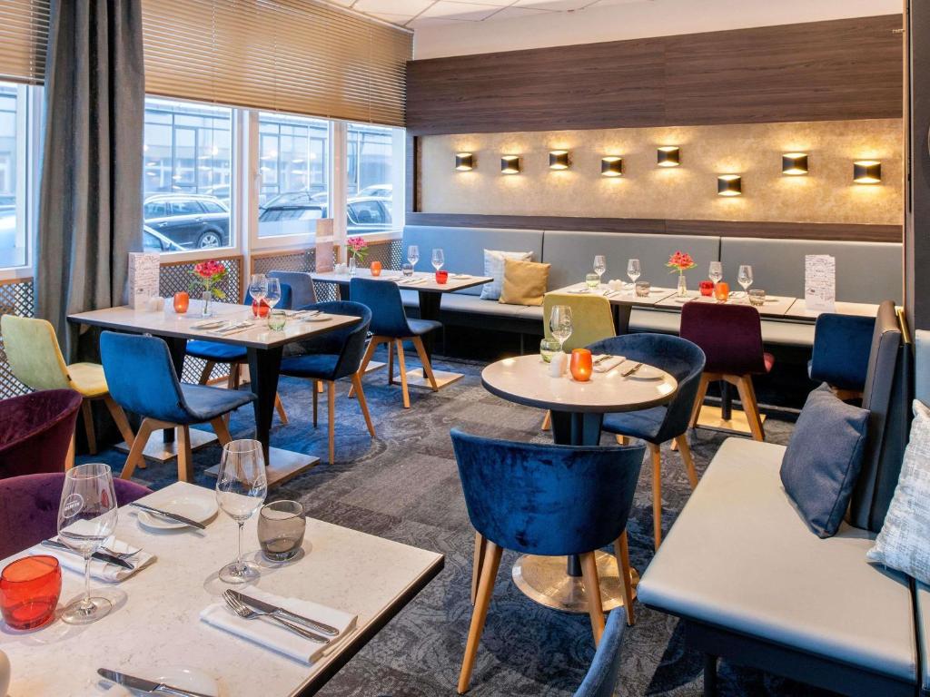 a restaurant with tables and chairs and windows at Mercure Hotel Hannover City in Hannover