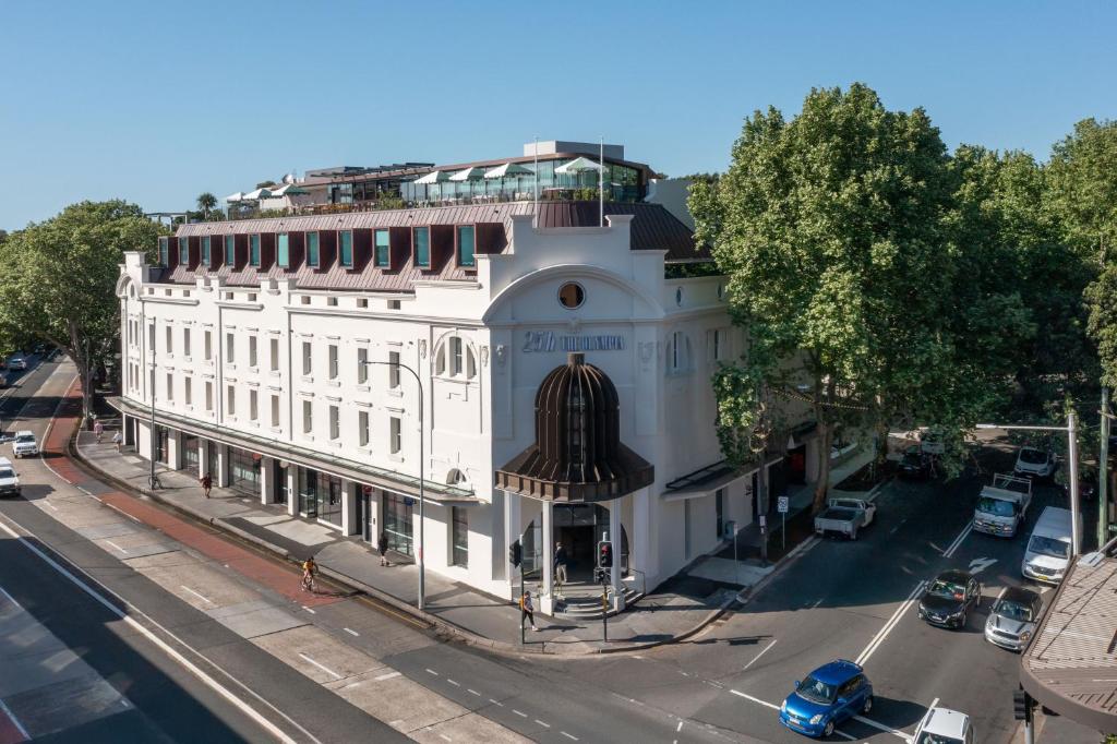 a large white building on the corner of a street at 25hours Hotel Sydney The Olympia in Sydney