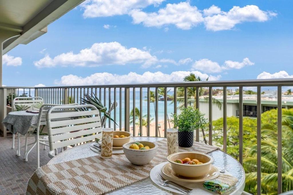 a table with bowls of fruit on a balcony at Whaler 712 · WHA 712 Kaanapali OceanFront Condo w Ocean Views in Lahaina