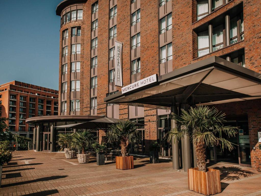 a building with umbrellas and palm trees in front of it at Mercure Hotel Hamburg City in Hamburg