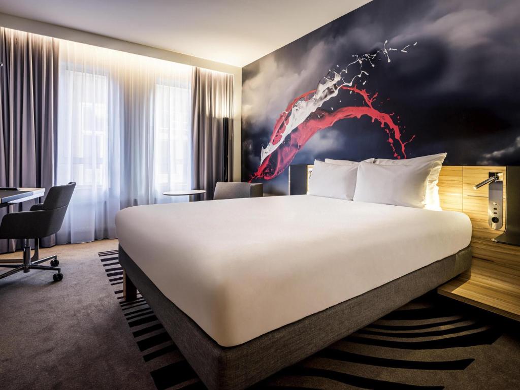 een hotelkamer met een groot bed en een rood schilderij bij Novotel Den Haag City Centre in Den Haag