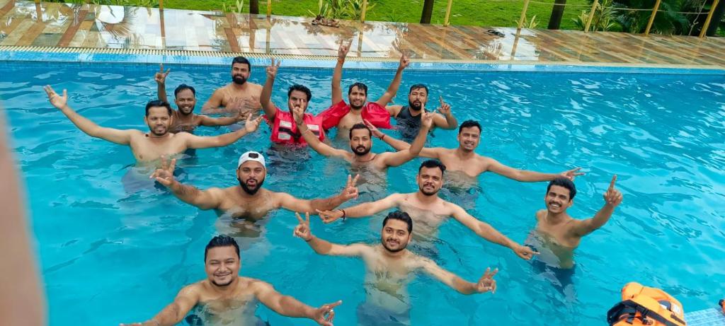 a group of men swimming in a swimming pool at Paradise Farm Alibaug in Kashid