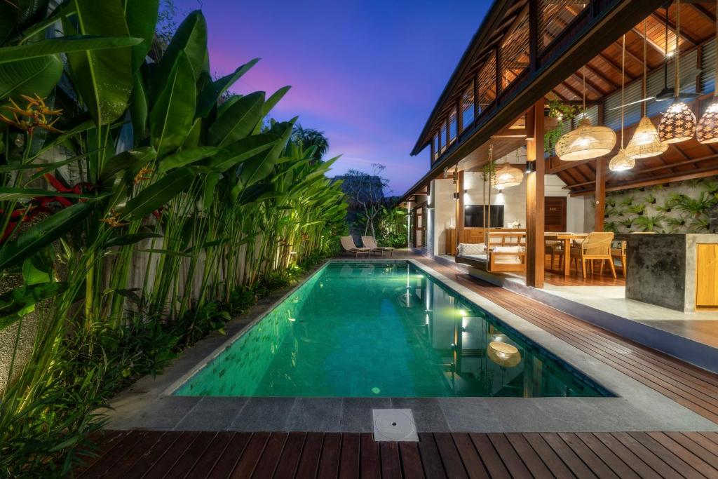 an infinity pool in a villa with a house at Dua villas Bali - Modern Balinese Escape in Canggu