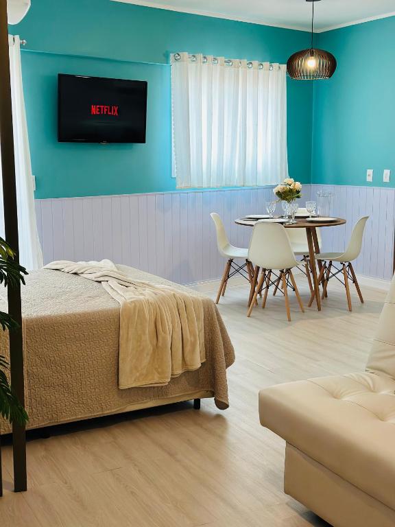 Una habitación con una cama, una mesa y un televisor. en Studio Aconchego Praia Grande, en Praia Grande