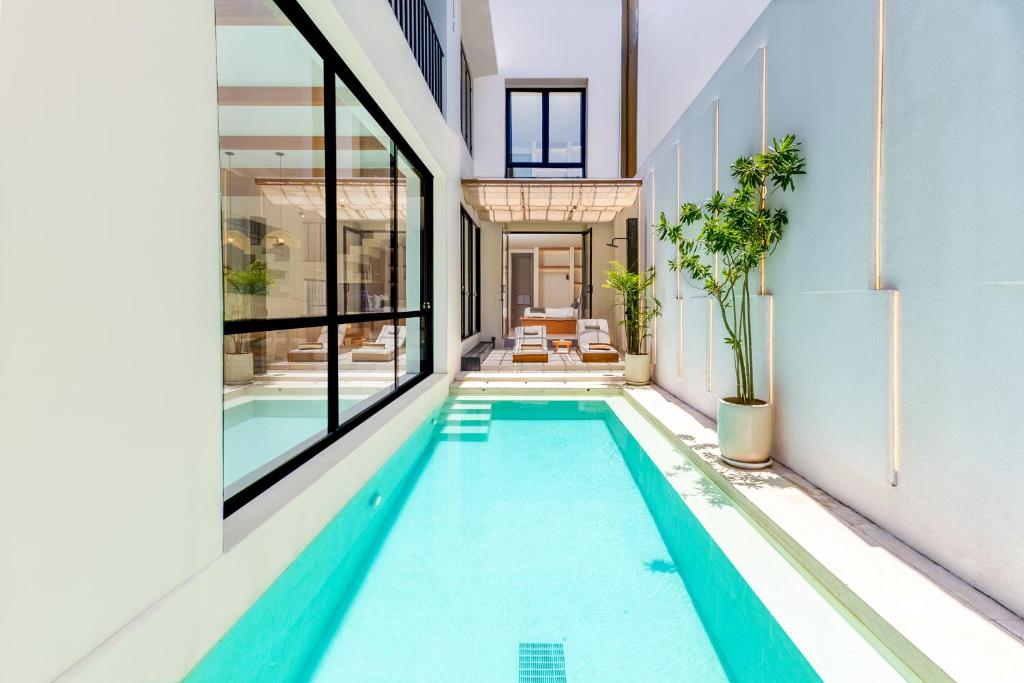 an indoor swimming pool in a building with windows at Villa Tin in Pererenan