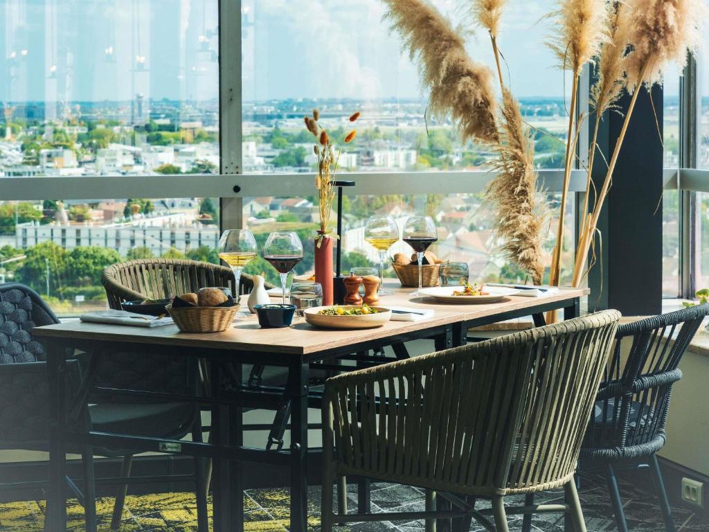 una mesa con sillas y copas de vino y comida en Mercure Paris Orly Rungis Aéroport, en Rungis