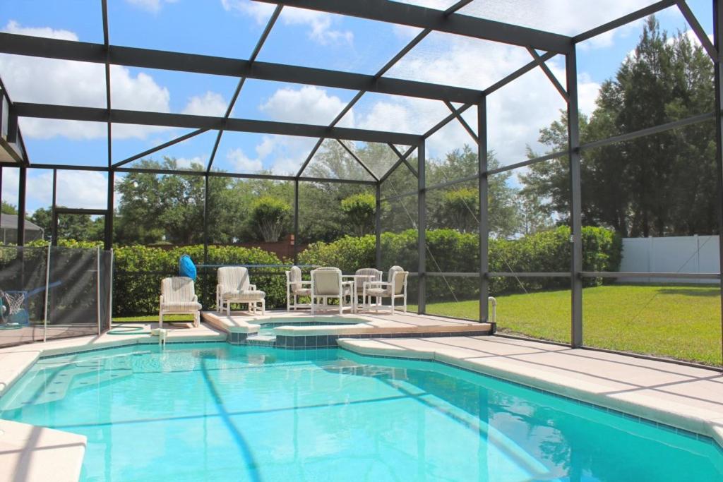 a swimming pool with a pergola and chairs next to it at Berkeley Pool Home home in Kissimmee