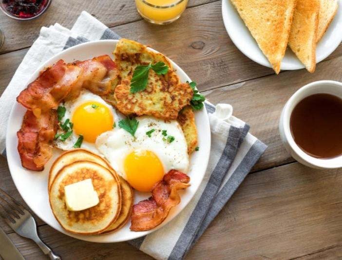 a plate of breakfast food with eggs bacon and toast at Little J villa in Dickwella