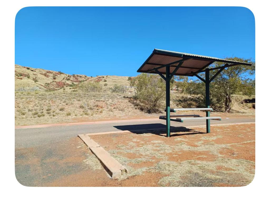 una parada de autobús con un banco al lado de una carretera en The studio on Ridley, en Karratha
