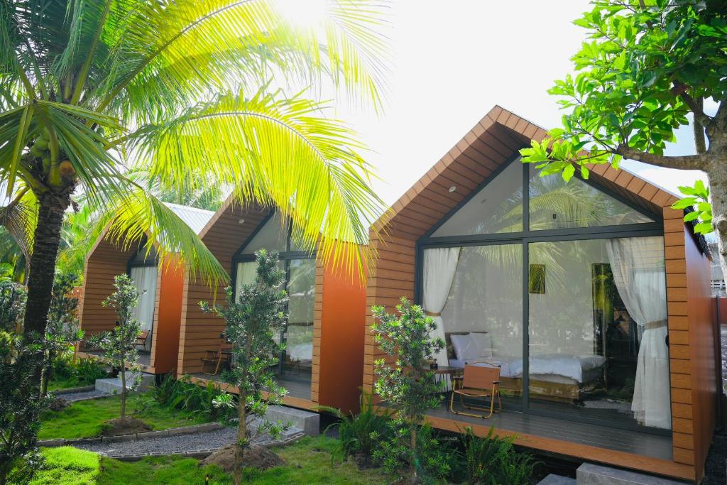 a house with glass windows and a palm tree at Biển Tôm ốc Homestay Bến Tre - Hồ Bơi & BBQ Garden in Ấp Sơn Thuận (2)