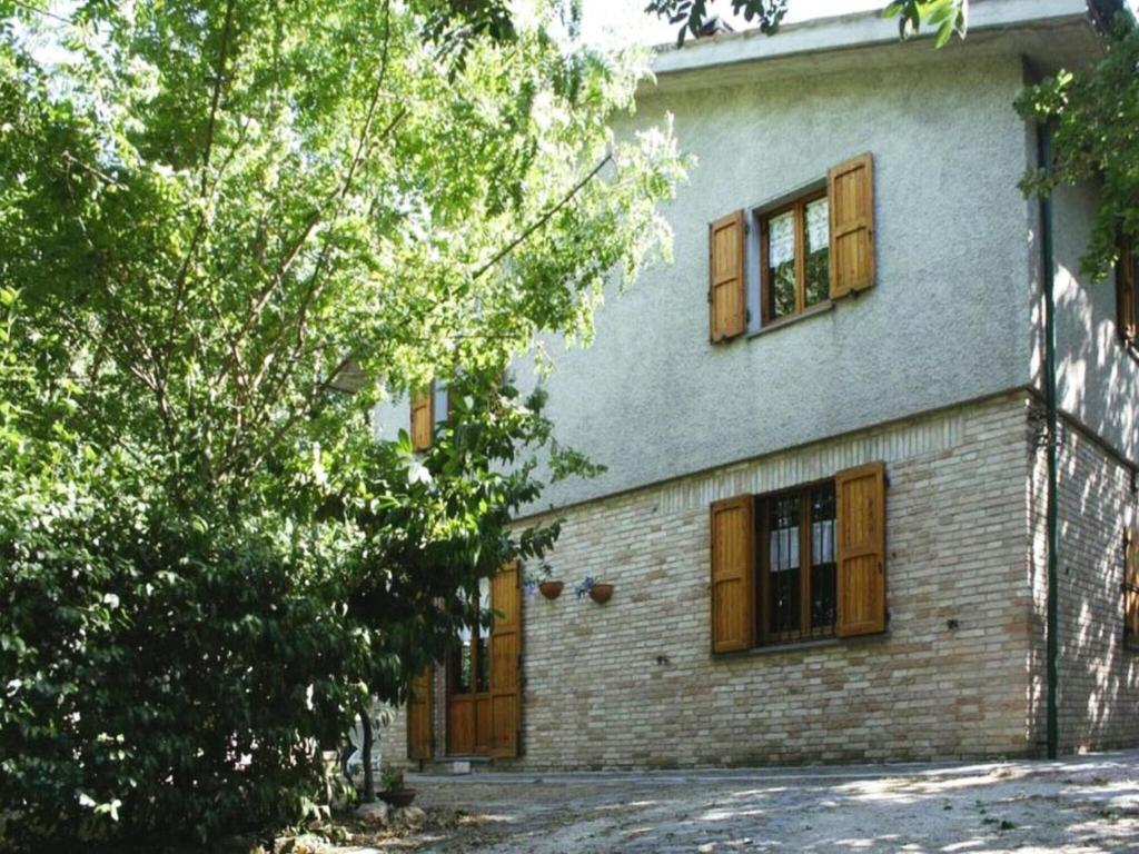 a brick house with wooden windows and a tree at Farmhouse in Fano with Pool & Adriatic Views in Montemaggiore al Metauro
