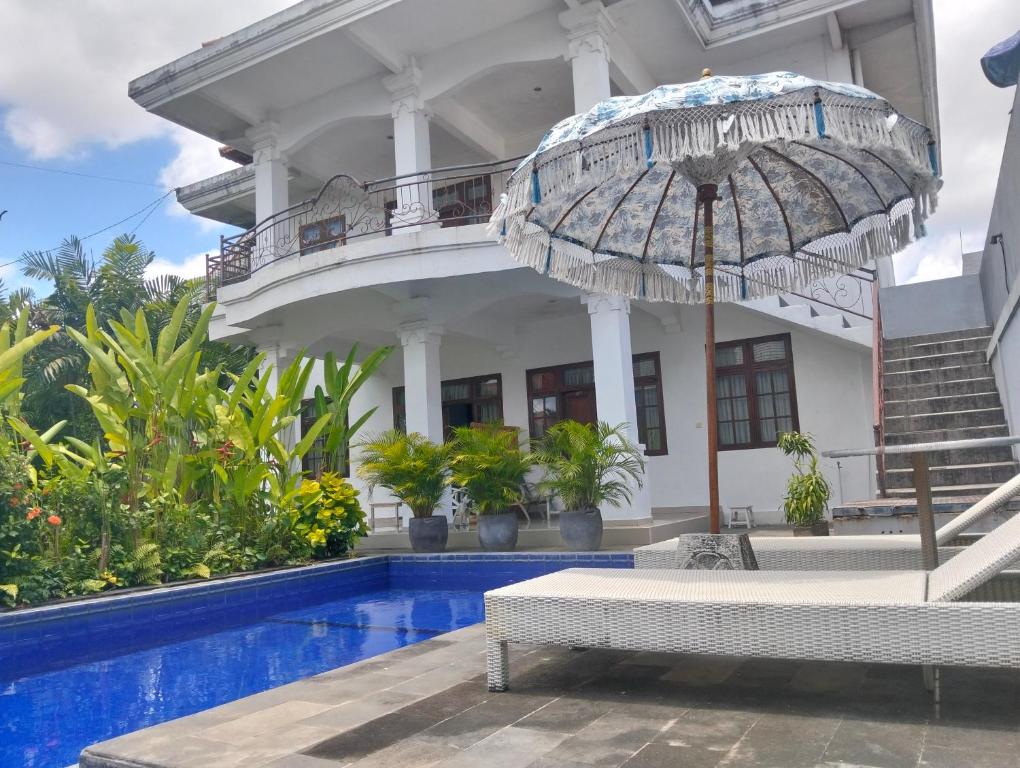 una casa con piscina y sombrilla en Merry's House canggu, en Canggu