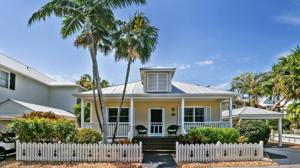 ストック・アイランドにあるPlace to Relax by AvantStay Shared Pool 3 Miles to Smathers Beach Month-Long Stays Onlyのヤシの木と白い柵のある家