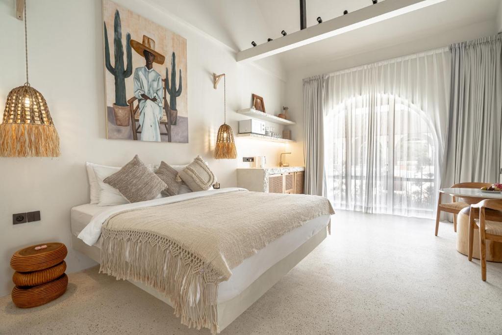 サヌールにあるMaison Bohemeの大きなベッドとテーブルのある白い寝室