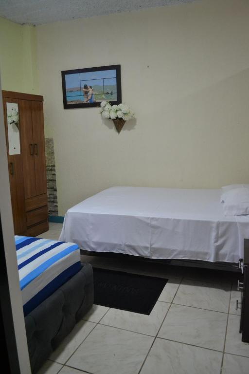 une chambre avec un lit et un tableau au mur dans l'établissement Casa Albacora, à Puerto Baquerizo Moreno