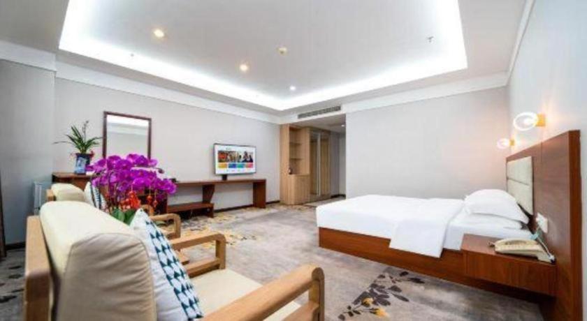 une chambre avec un lit et un bureau dans une pièce dans l'établissement Bashan Hotel, à Xiamen