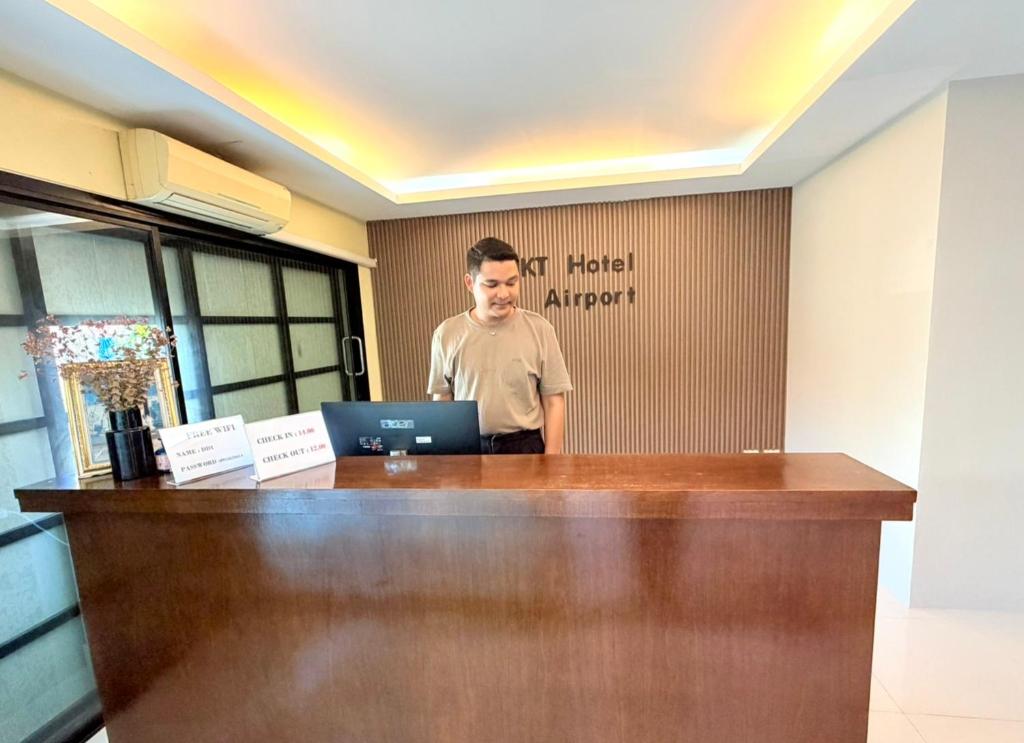 a man standing behind a desk with a laptop at KT Hotel Airport in Nai Yang Beach