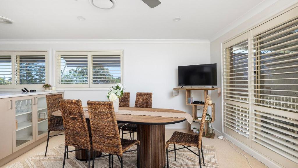 a dining room with a table and some windows at 2-5 The Meridian, Corlette in Corlette