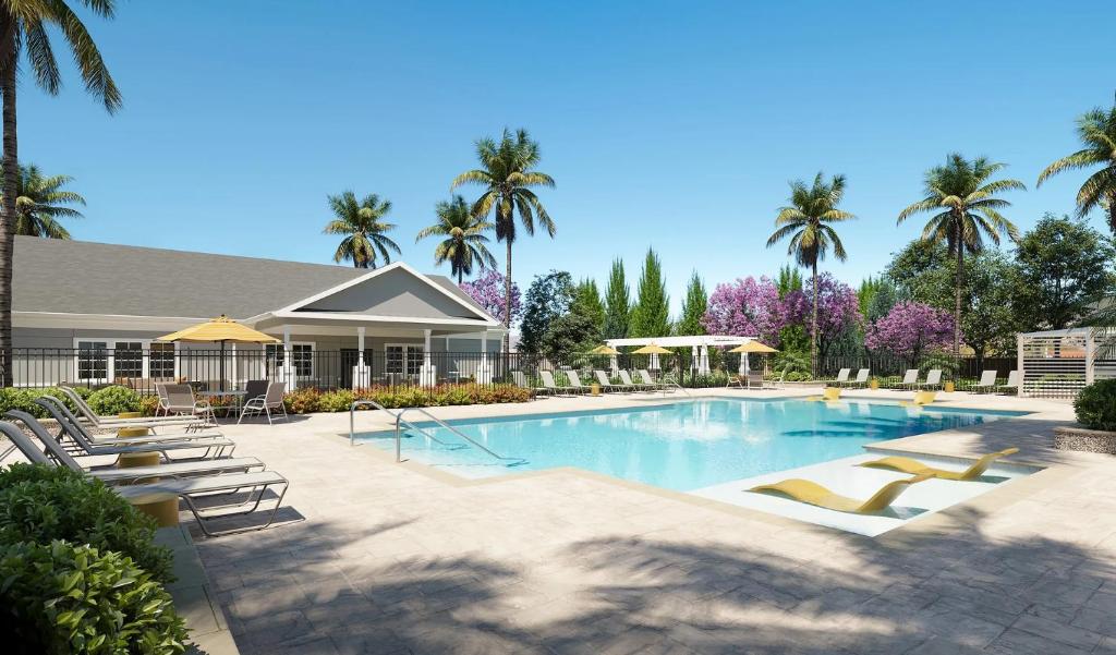 una piscina con tumbonas y palmeras en Landing Apartments Palm Bay, en Palm Bay