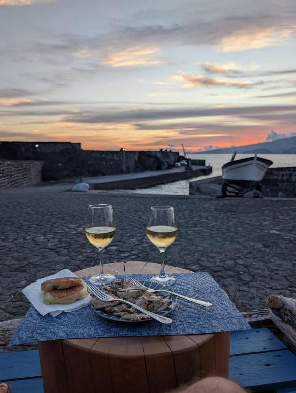 a table with two glasses of wine and food on the beach at Casa do Cais in Monte