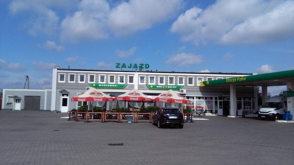 a large white building with umbrellas in a parking lot at Zajazd Markowski in Bojanowo
