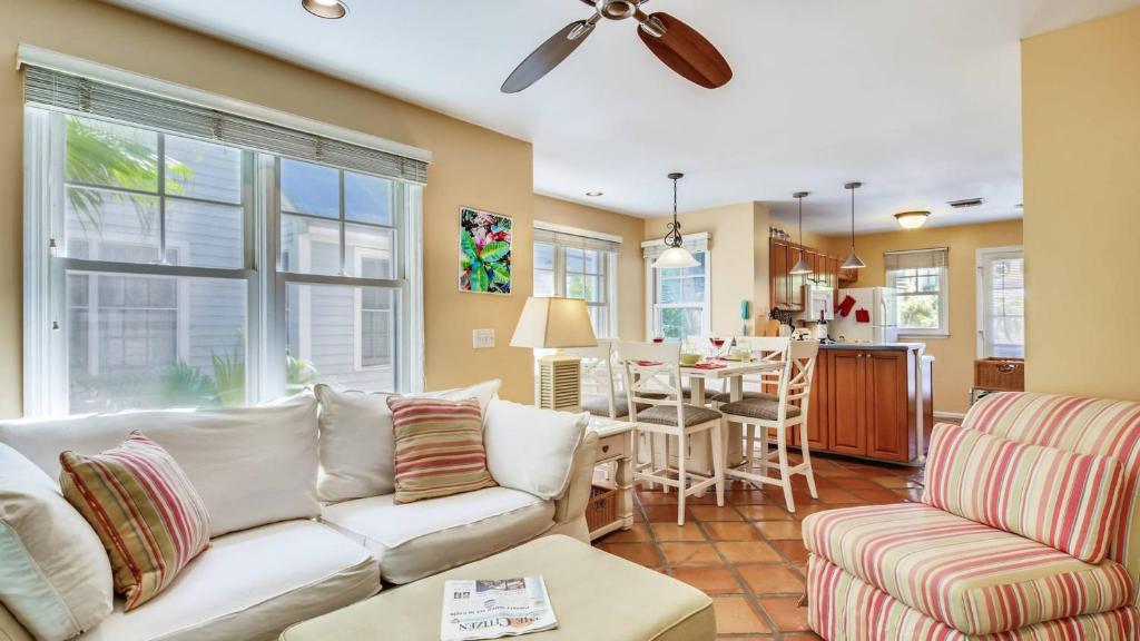 Cottage by the Pool by AvantStay w Balcony BBQ Shared Pool Month Long Stays Only في ستوك آيلاند: غرفة معيشة مع أريكة وغرفة طعام