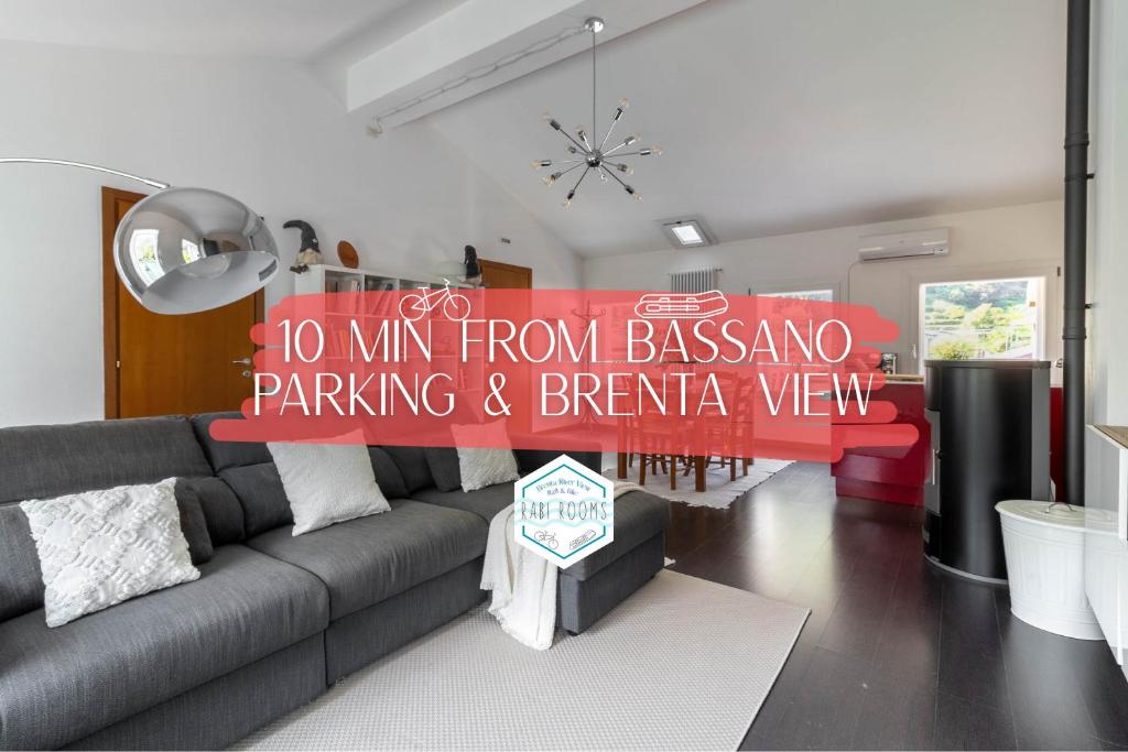 a living room with a gray couch and a sign at RaBi Apart - Rafting & Bike Apart in Valbrenta 