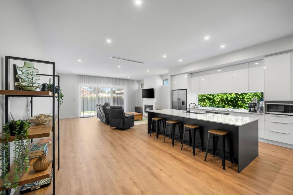 an open kitchen and living room with a large island at Belle Escapes - Henley Beach House in Henley Beach