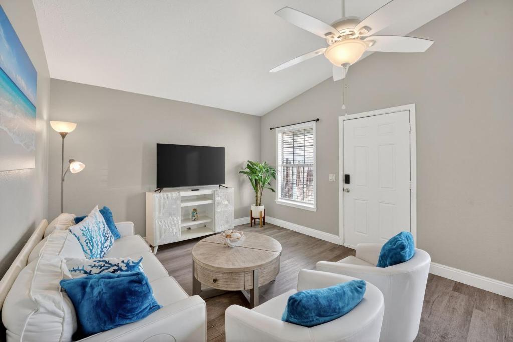 a living room with white furniture and a flat screen tv at Luxury Beach Access in Panama City Beach