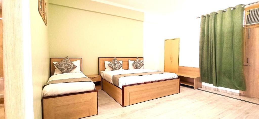 2 camas en una habitación con cortinas verdes en Shri Thakur Ji Niketan, en Vrindāvan