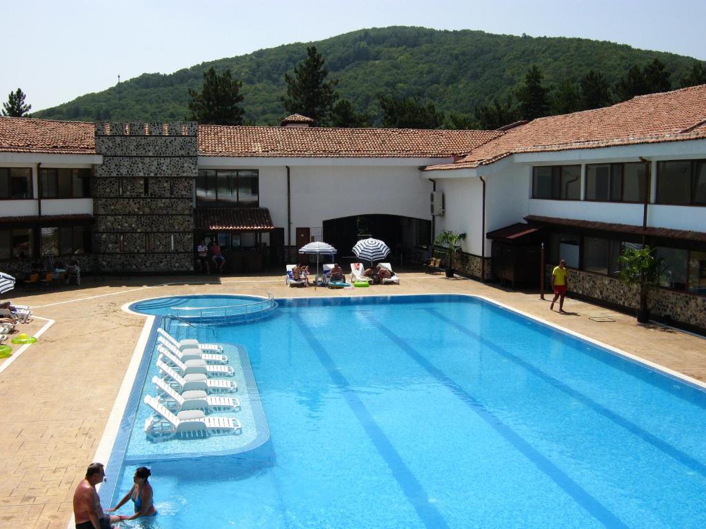 ein großer Pool mit zwei Personen neben einem Gebäude in der Unterkunft Motel Koziyat Rog in Malko Tŭrnovo