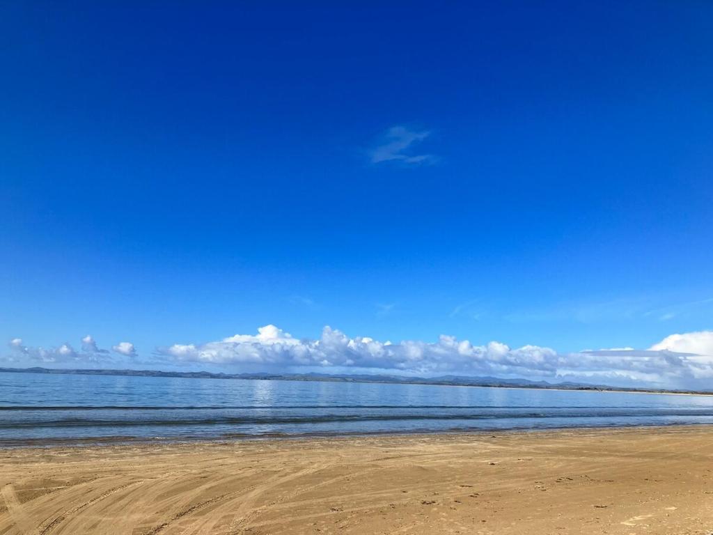 una spiaggia con l'oceano e le nuvole nel cielo di The Sandy Jandal a Karikari Peninsula