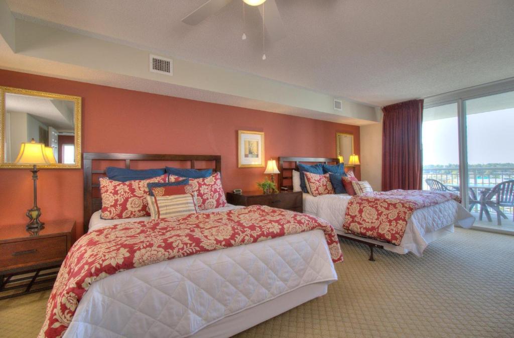 a large bedroom with two beds and a balcony at Barefoot Yacht Club Villas - 1-805 in Myrtle Beach