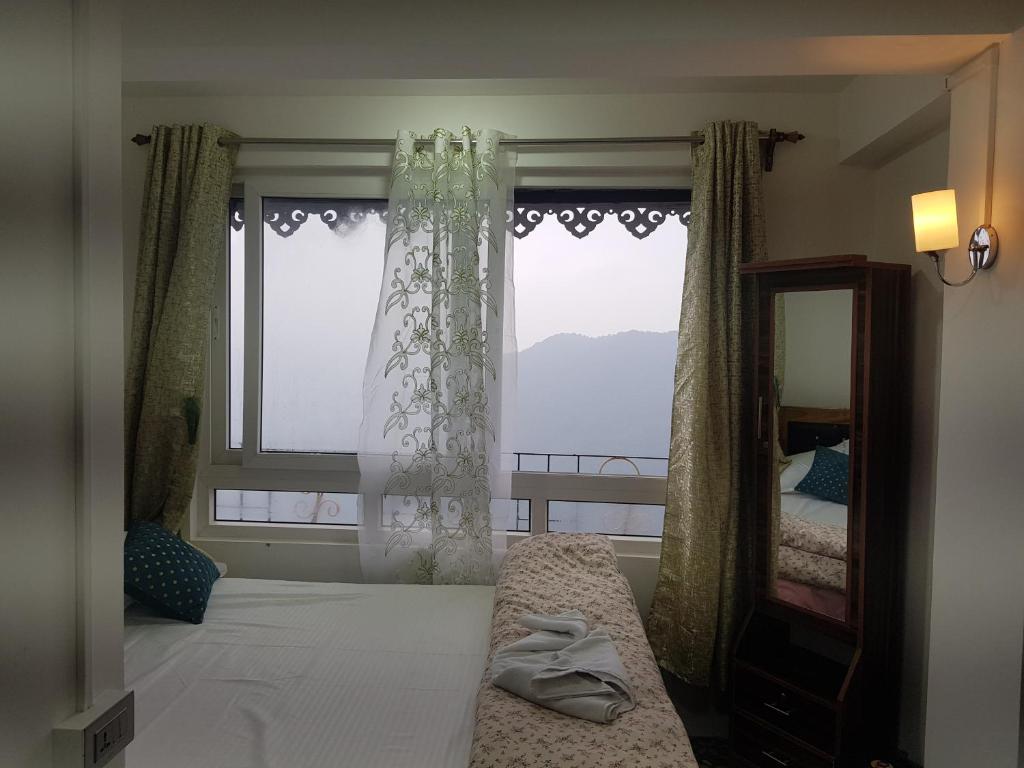 a bedroom with a bed and a mirror and a window at Mannata Homesaty in Darjeeling