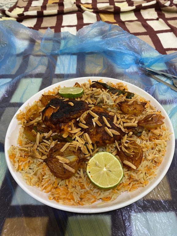 ein weißer Teller mit Essen mit Reis und einer Limette in der Unterkunft Wadi rum sky luxury in Wadi Rum