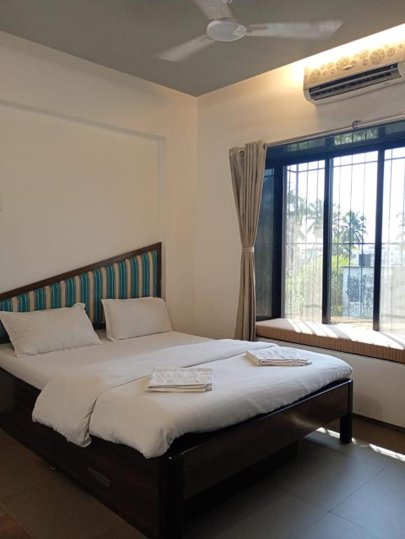 a bedroom with a large bed and a window at Alibag Beach Stay- The Grantley Hotel in Alibag