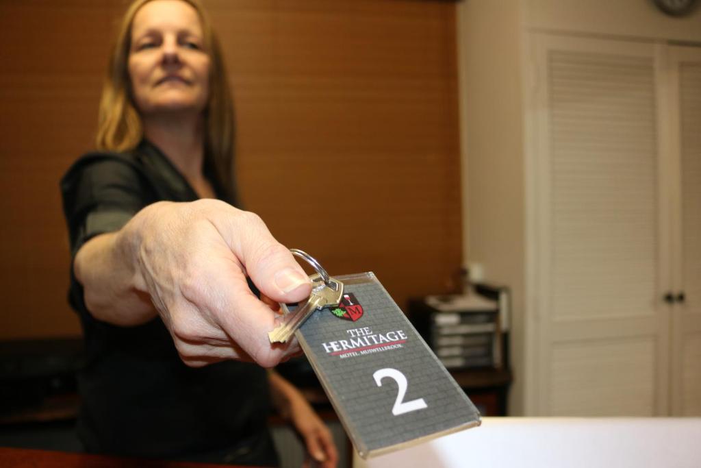 a woman holding up a small piece of paper at Hermitage Motel in Muswellbrook