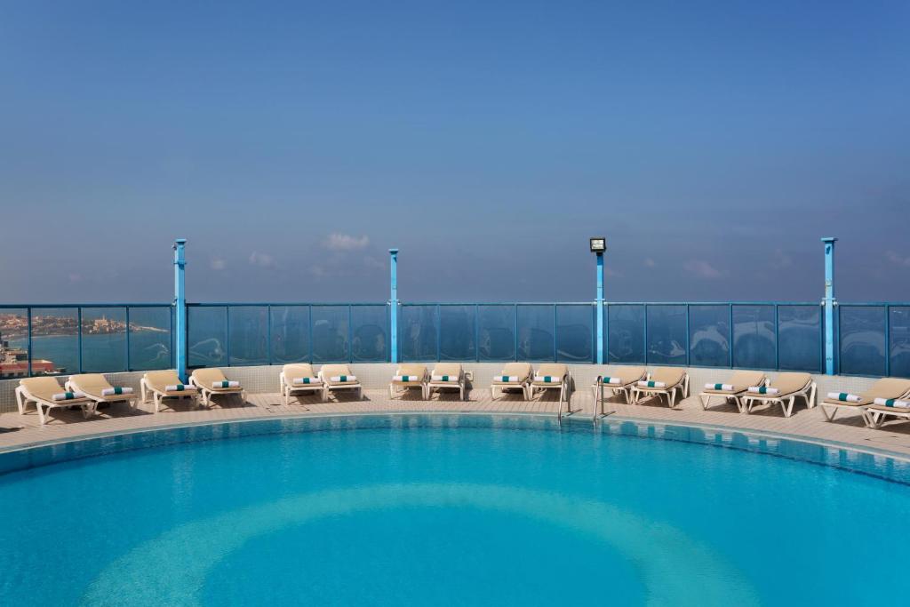 a swimming pool with chairs and tables on a balcony at Sea Tower by Isrotel Design in Tel Aviv