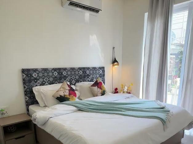 a bedroom with a white bed with a large window at PUNTUSH By The StayCationer in Dehradun