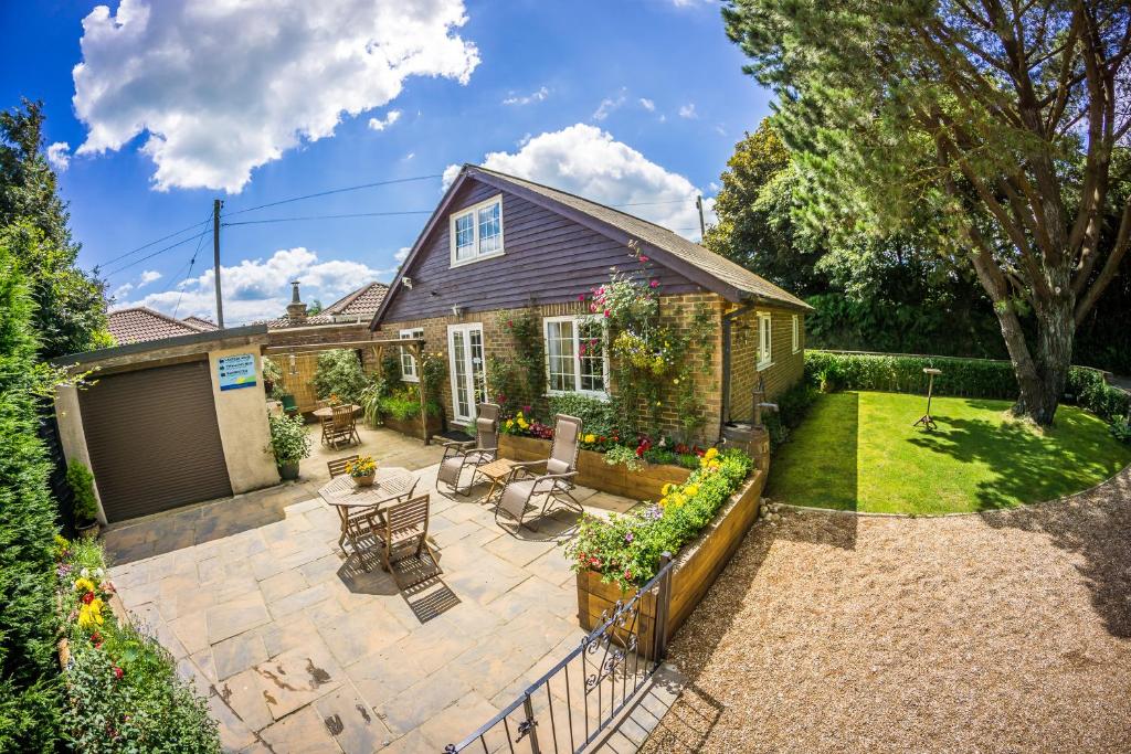 a patio with chairs and tables in a backyard at Swallows Nest - Covehurst Bay Cottage in Hastings