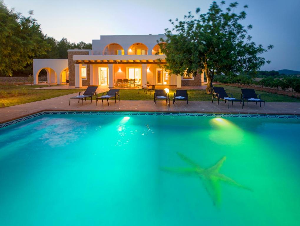 una casa con piscina frente a una casa en Es Casals Nou, en Santa Gertrudis