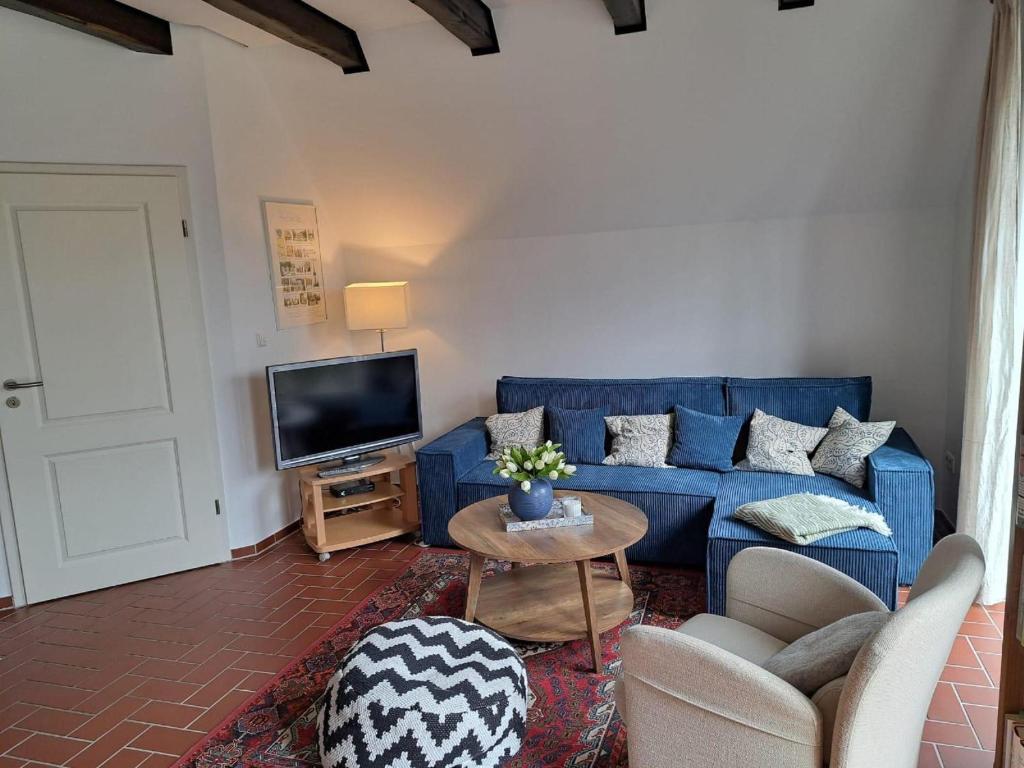 a living room with a blue couch and a tv at Ferienwohnung Rotbuche in Rastede