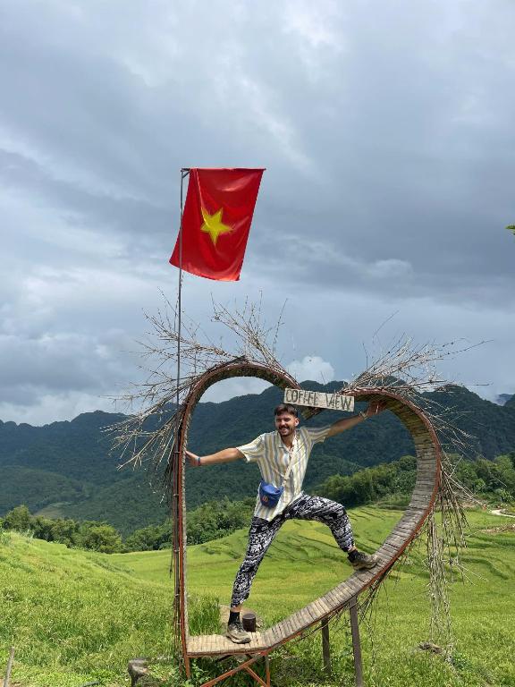 a man is standing on a rail with a flag at Mai Chau Bình Minh Hotel in Mai Châu